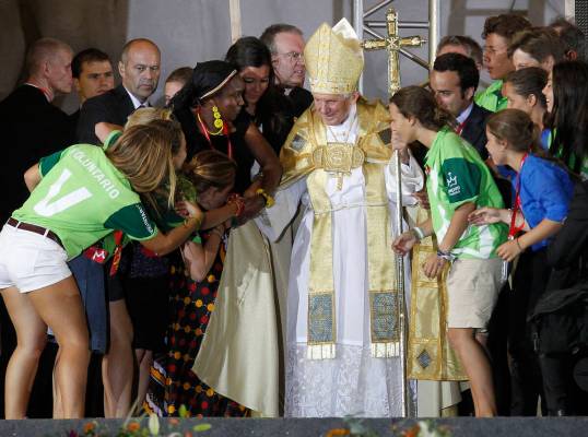 Pilgrims react as they approach Pope Benedict XVI and kiss his right hand, at Cuatro Vientos ai ...