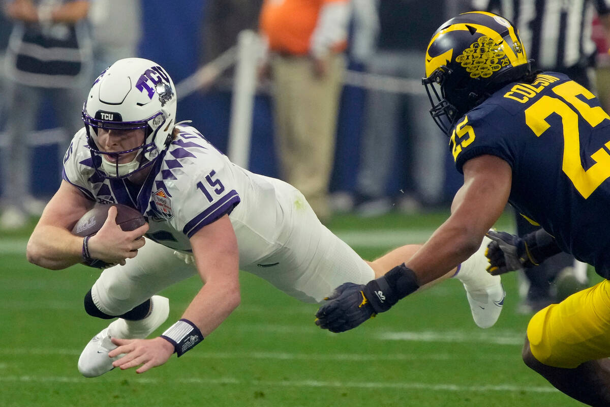 TCU quarterback Max Duggan (15) dives for yardage as Michigan linebacker Junior Colson (25) def ...