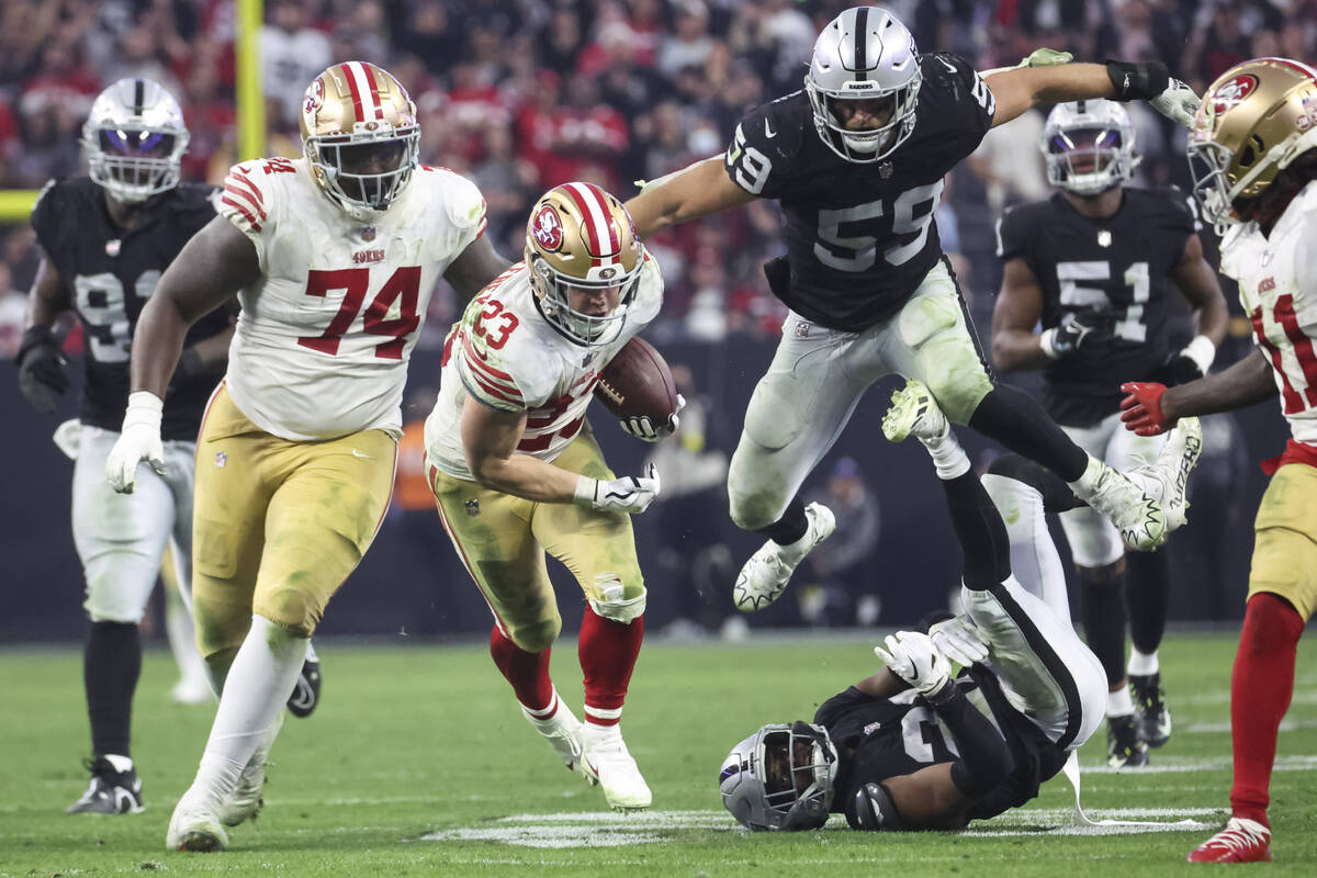 San Francisco 49ers running back Christian McCaffrey (23) runs the ball under pressure from Rai ...