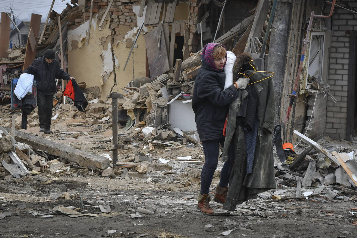 Local residents carry their belongings as they leave their home ruined in the Saturday Russian ...