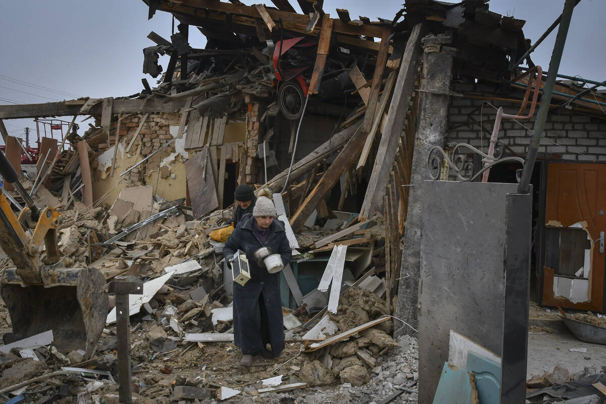 Local residents carry their belongings as they leave their home ruined in the Saturday Russian ...