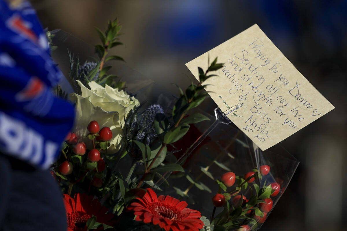 Carol Smith carries flowers for the display set-up for Buffalo Bills' Damar Hamlin outside of U ...