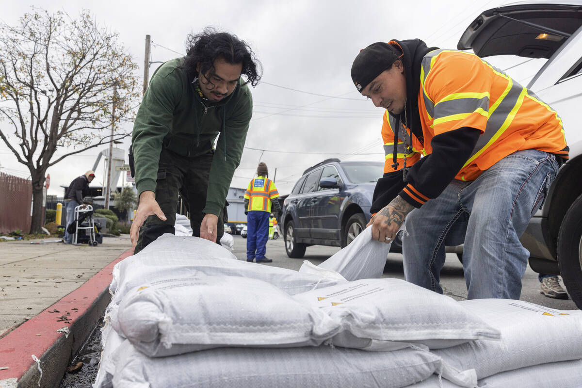 Fernando Bizarro, left, collects sandbags from an emergency distribution center to prepare for ...