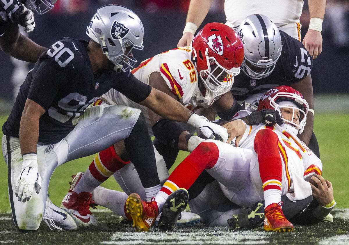 Kansas City Chiefs quarterback Patrick Mahomes (15) is dragged backwards onto the turn by Raide ...