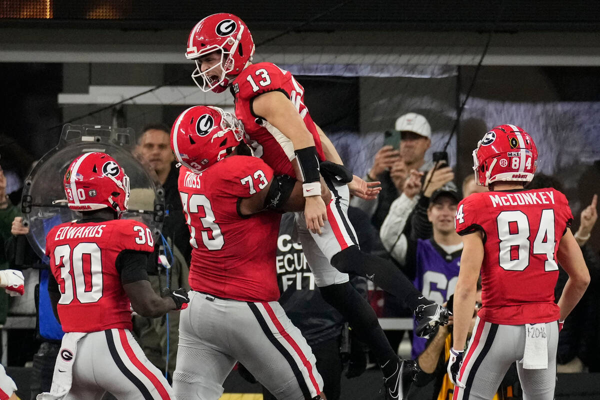 Georgia offensive lineman Xavier Truss (73) lifts Georgia quarterback Stetson Bennett (13) afte ...