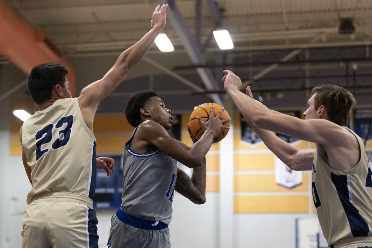 Desert Pines’ Evan Tatum (11) passes between Foothill’s Shawn Salazar (23) and Br ...