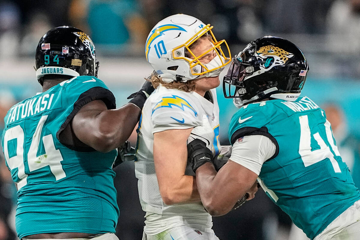 Los Angeles Chargers quarterback Justin Herbert (10) is hit by Jacksonville Jaguars linebacker ...