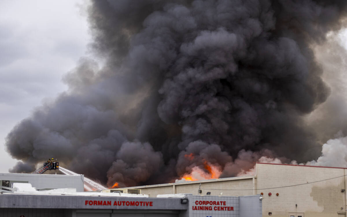 Black smoke and flames rise into the sky as Las Vegas and Clark County Firefighters work a full ...