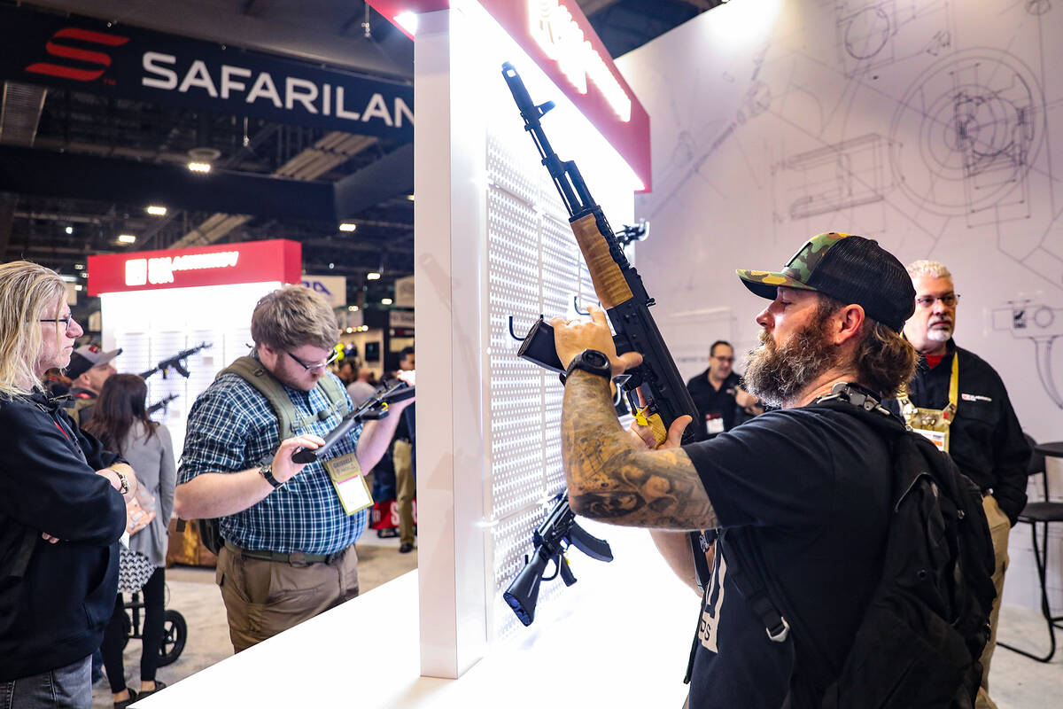 Lee Moiseve, from San Diego, Calif., checks out a gun at the Shooting, Hunting and Outdoors tra ...