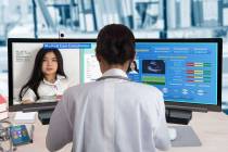 Female doctor working with two computers for distance patient consultation and searching her he ...