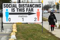 FILE - A person walks past a COVID-19 restrictions sign during the COVID-19 pandemic in Mississ ...