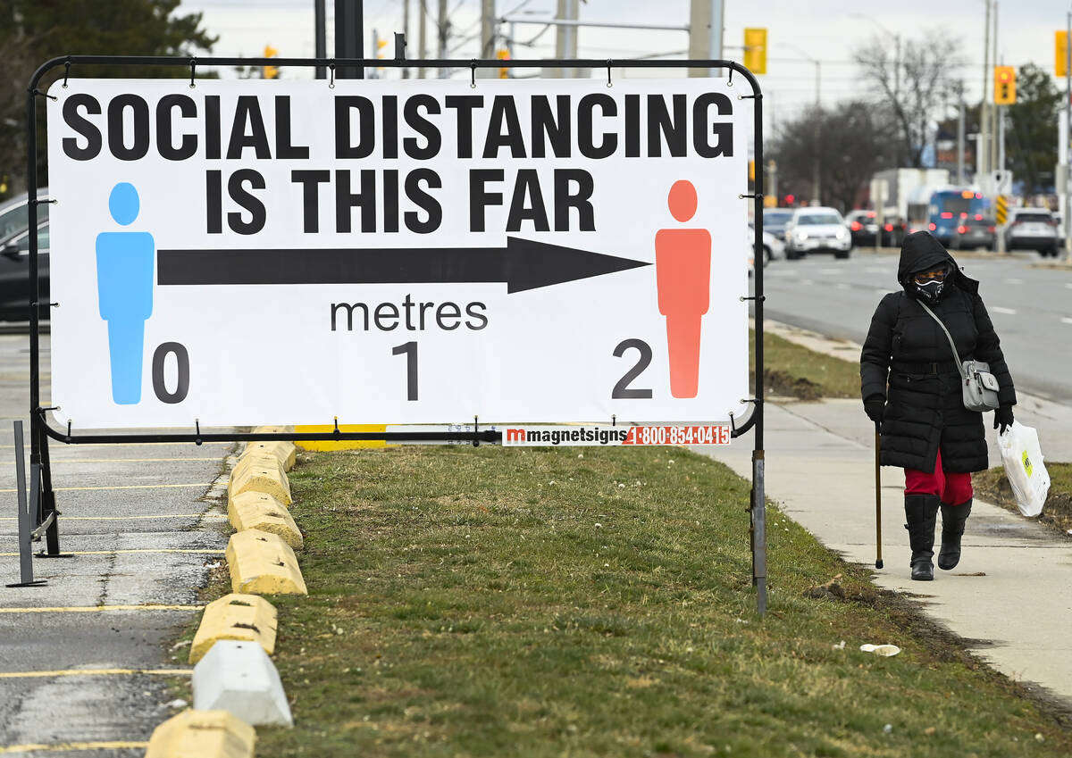 FILE - A person walks past a COVID-19 restrictions sign during the COVID-19 pandemic in Mississ ...