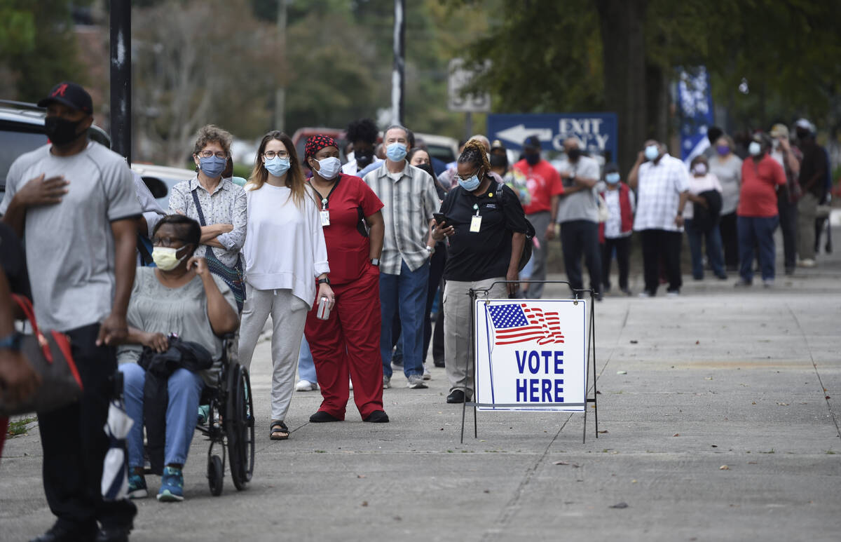 In this Oct. 12, 2020, file photo, people wait in line for early voting at the Bell Auditorium ...