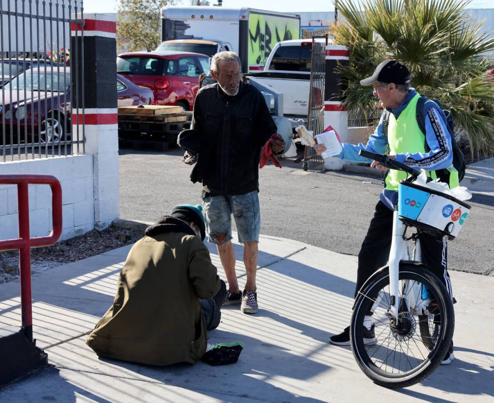 Richard Birmingham, right, offers food and resource information to Gabriel Capone, left, and Ri ...