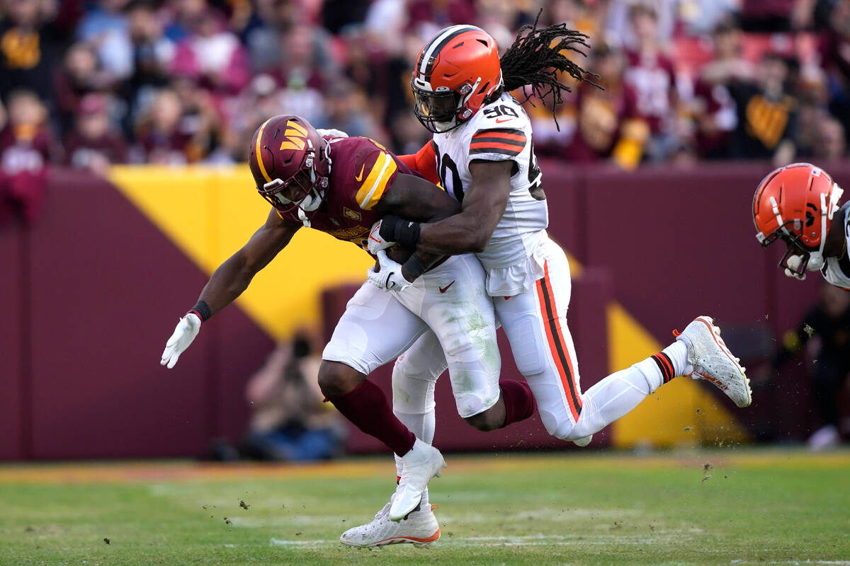 Cleveland Browns defensive end Jadeveon Clowney (90) tackles Washington Commanders running back ...