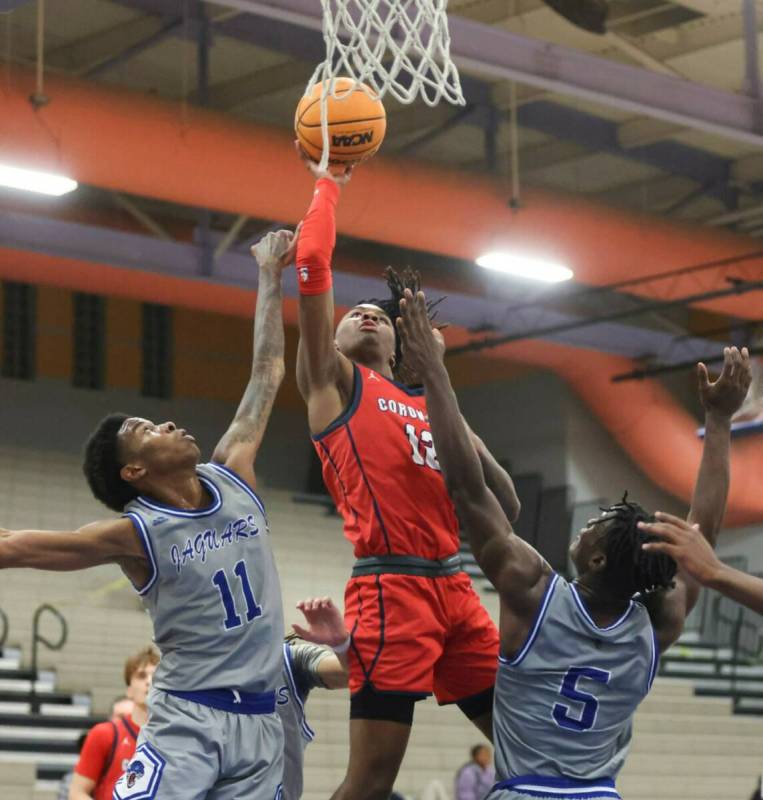 Coronado's guard Sebastian Mack (12) shoots between Desert Pines' Evan Tatum (11) and Greg Burr ...