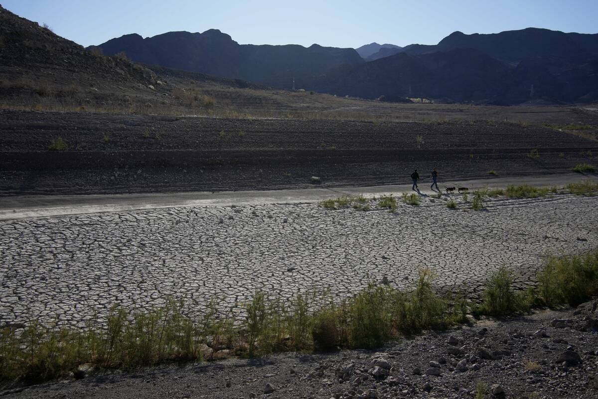 People walk by cracked earth in an area once under the water of Lake Mead at the Lake Mead Nati ...