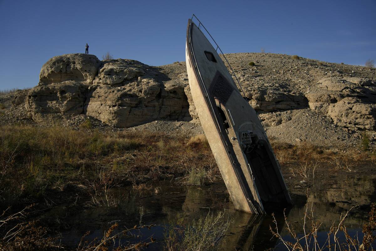 A man stands on a hill overlooking a formerly sunken boat standing upright into the air with it ...