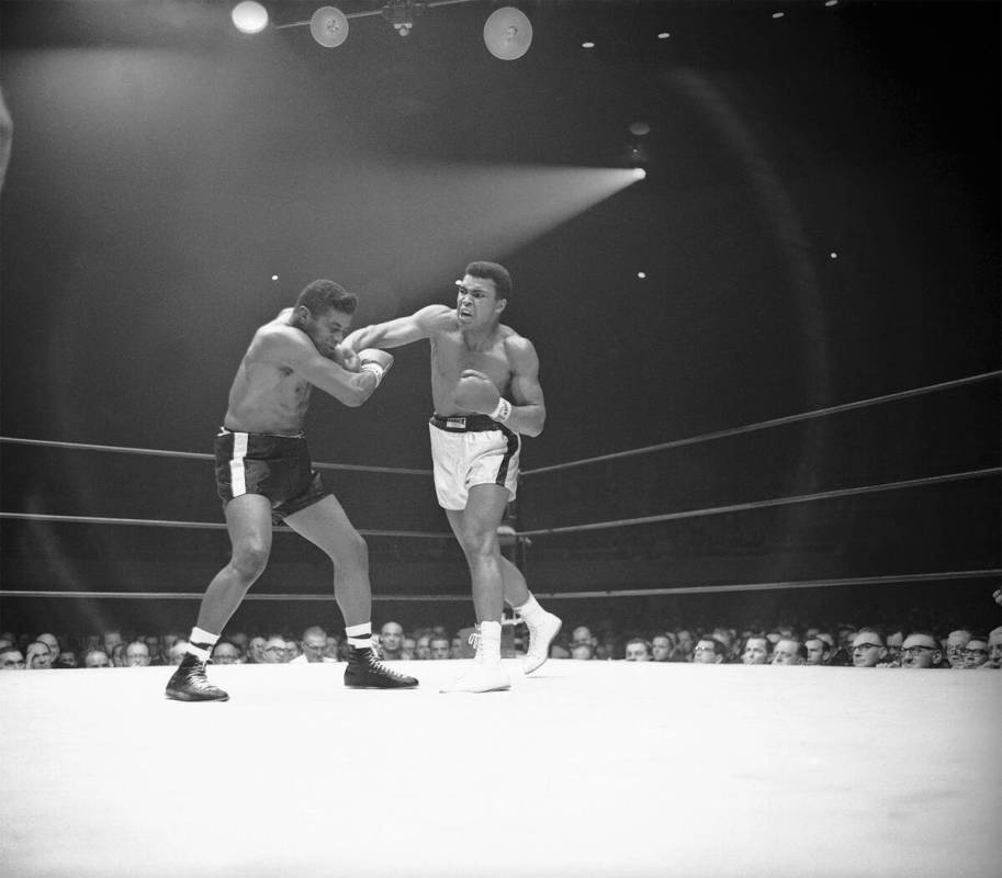 Heavyweight champion Muhammad Ali ( Cassius Clay) moves in with a series of amsshes to the f ...