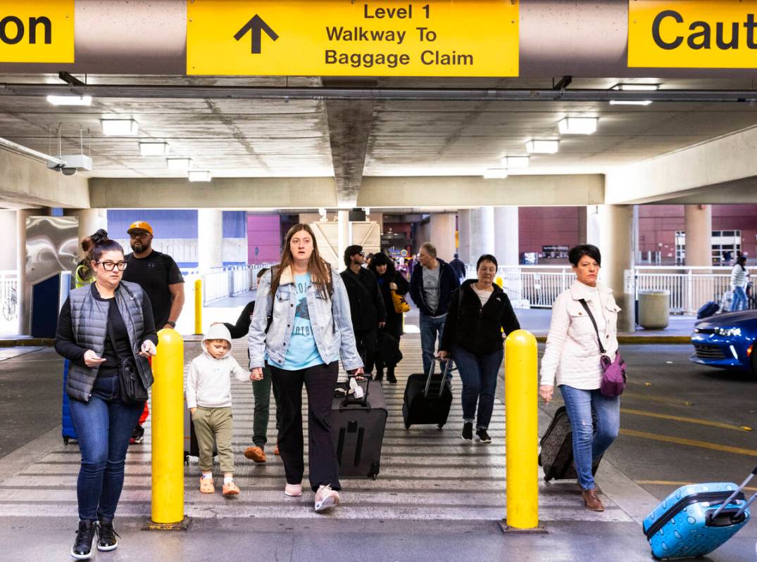 Arriving passengers walk to retrieve their vehicles from the level 2 of Terminal 1 parking lot ...