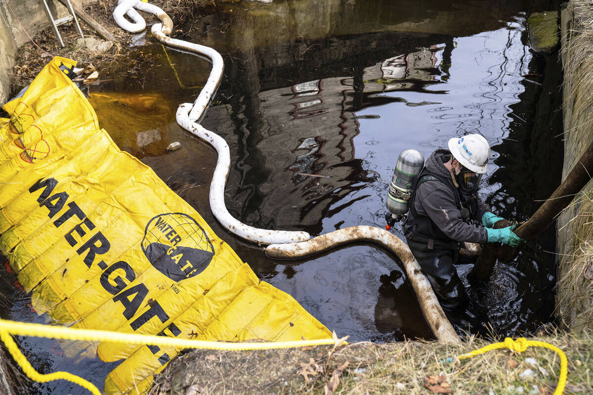 An employee of HEPACO works in a creek along Sumner Street in downtown East Palestine, Ohio, on ...