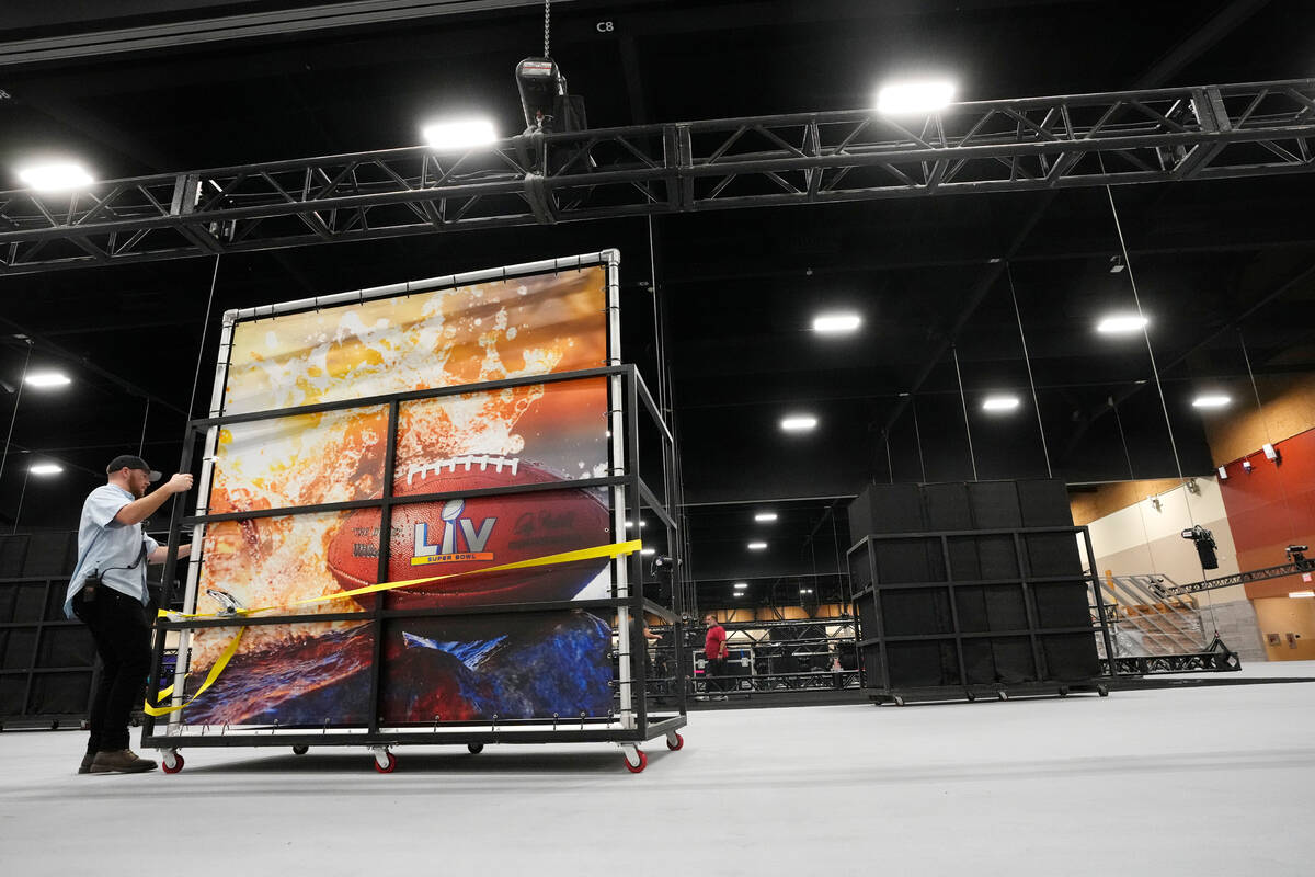 A worker arrives with a Super Bowl logo mural as the Super Bowl Experience is built at the Phoe ...