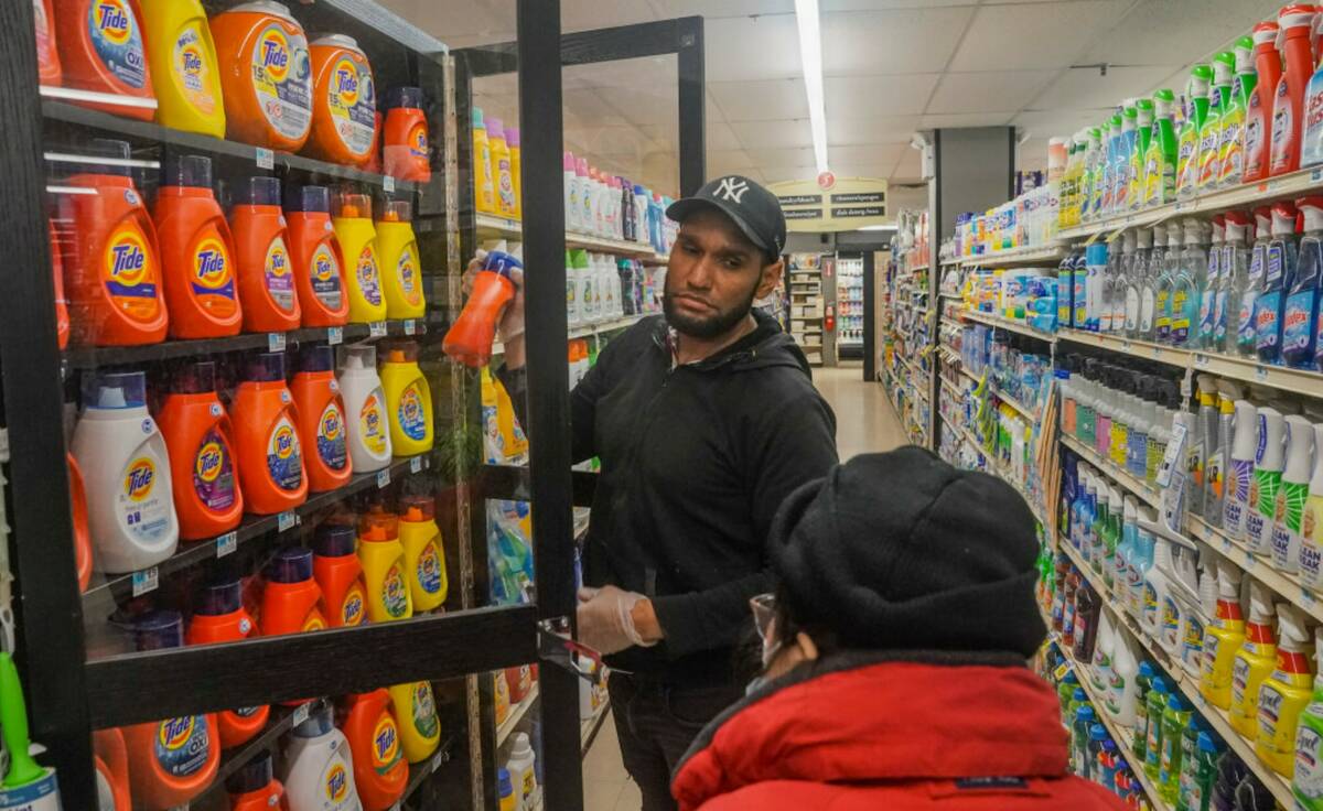 Leo Pichardo, left, a store associate at Gristedes supermarket, retrieves a container of Tide l ...