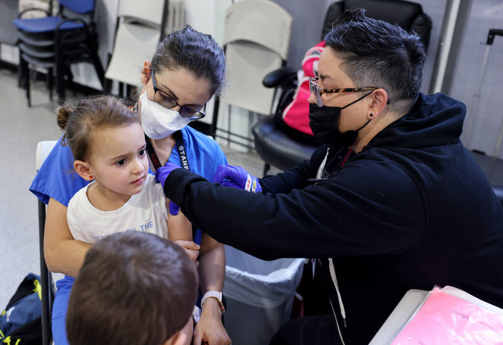 Mais Yacoub holds her 3-year-old daughter Quincy as she gets a COVID-19 vaccine from KJ Dionisi ...