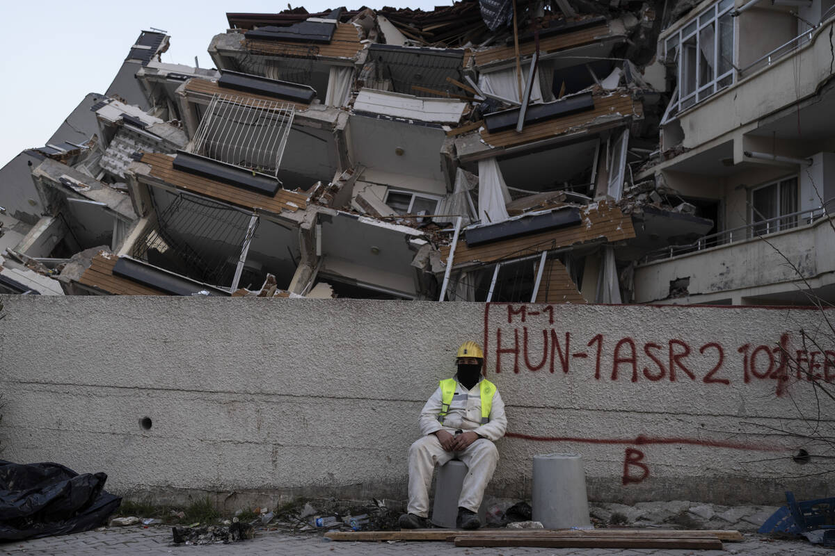 A rescue worker rests as others continue the search for victims of the earthquake in Antakya, T ...