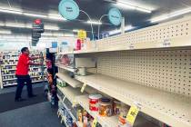 An employee walks near empty shelves where baby formula would normally be located at a CVS in N ...