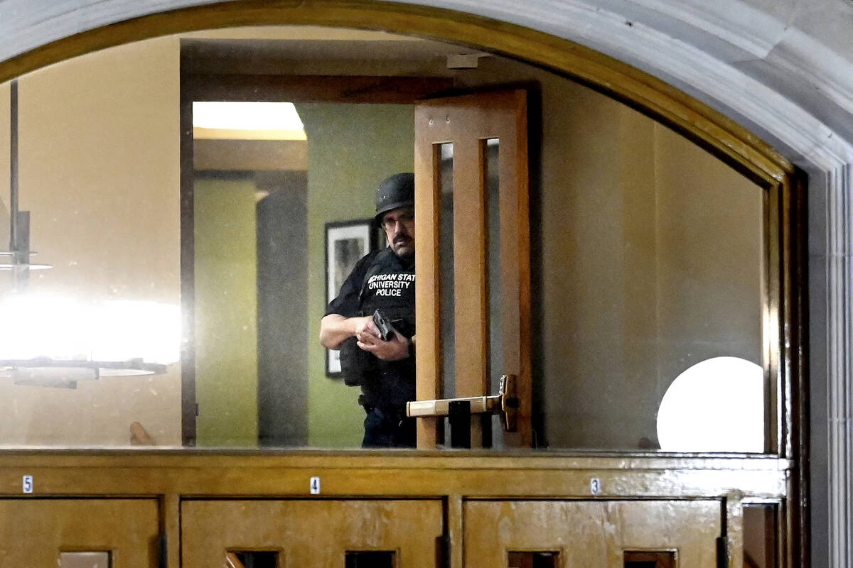 A police officer, with his gun drawn, is seen through the window at an entrance at the Michigan ...