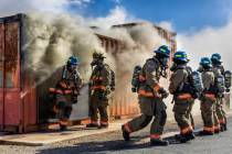 Clark County Fire Department recruits exit a smoky trailer during live fire training at the tra ...