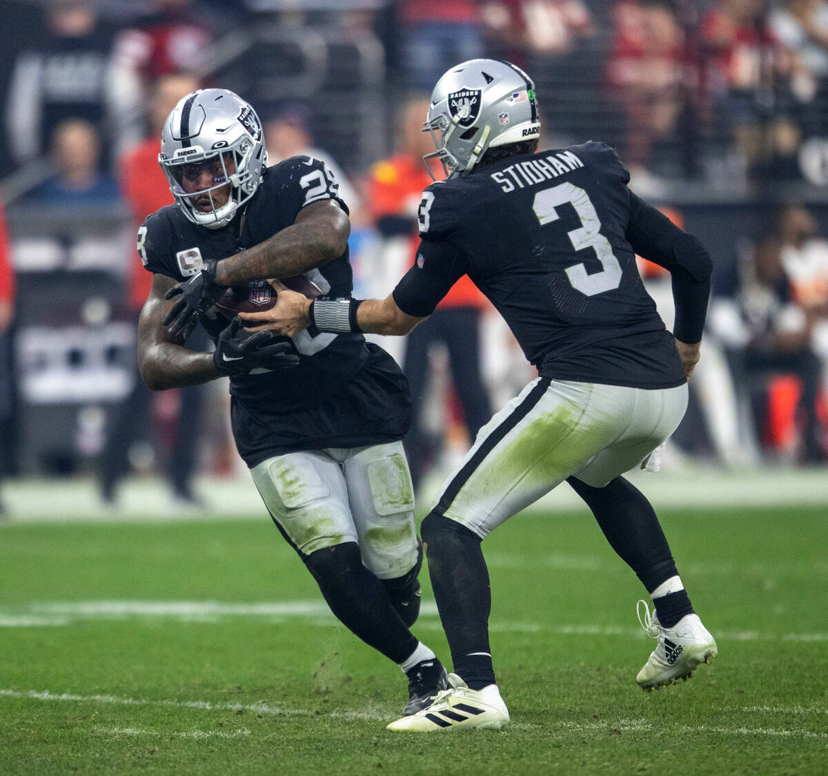 Raiders quarterback Jarrett Stidham (3) hands off to Raiders running back Josh Jacobs (28) duri ...