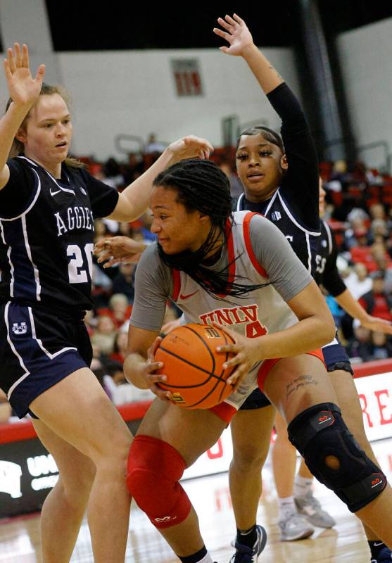 UNLV Lady Rebels forward Alyssa Brown (44), center, keeps a ball away from Utah State Aggies fo ...