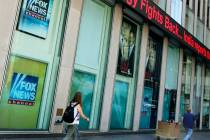 People pass the News Corporation headquarters building and Fox News studios in New York on Aug. ...