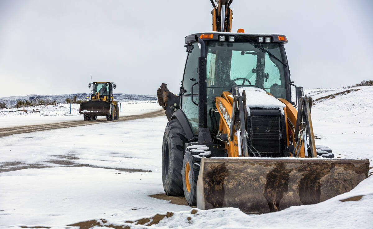 A construction worker makes his way along as snow covers the ground along Kettle Ridge Drive as ...