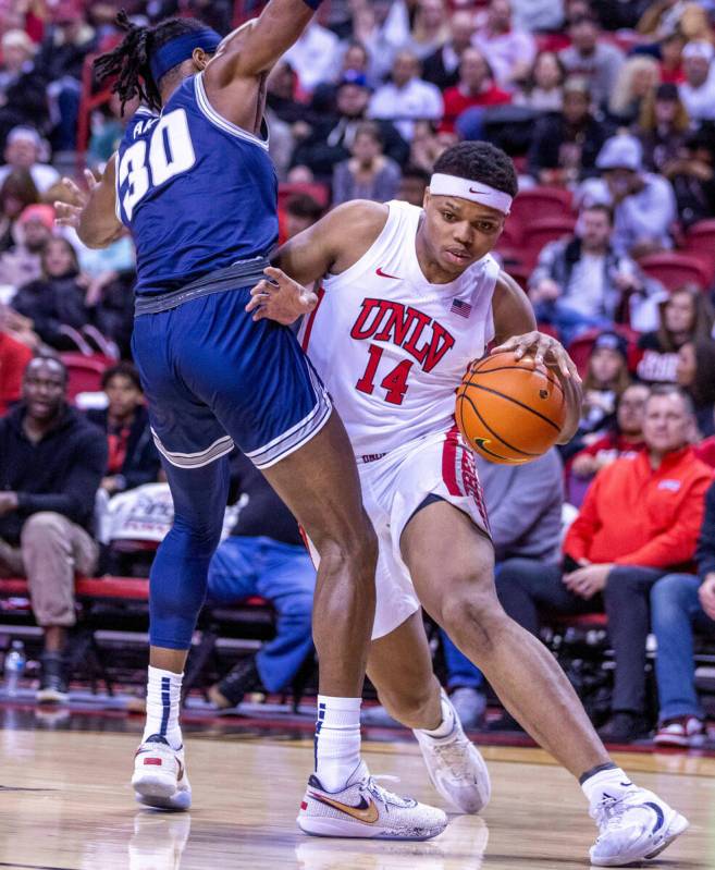 UNLV guard Keyshawn Hall (14) fights to get around the defense of Utah State forward Dan Akin ( ...