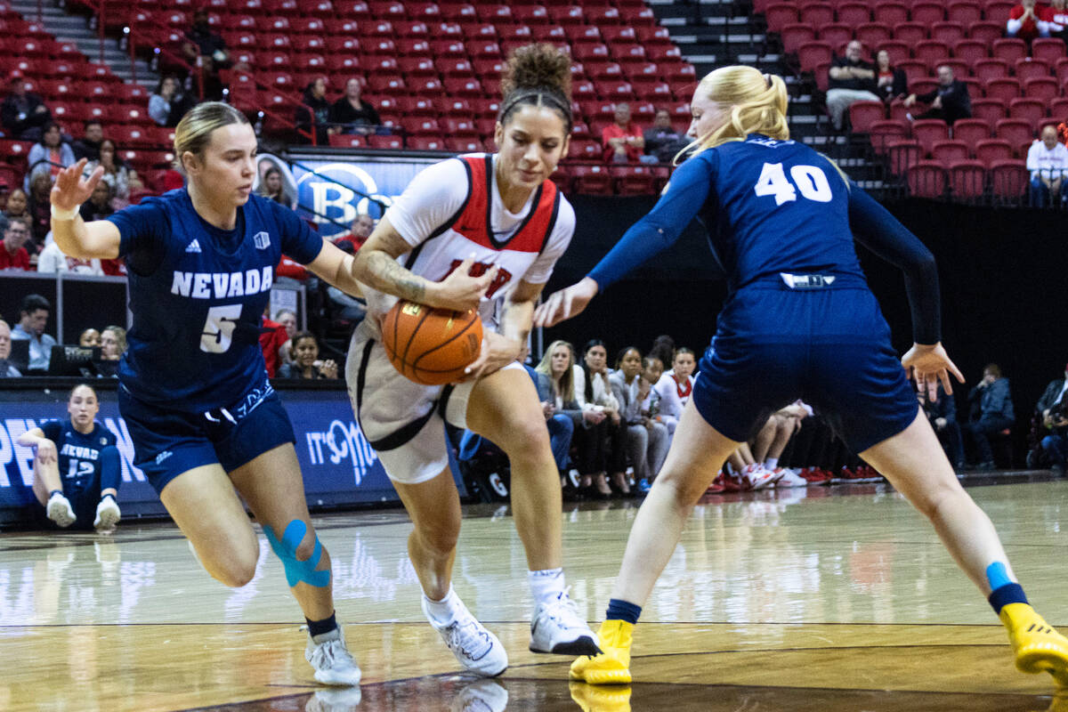 UNLV Lady Rebels guard Essence Booker (24) drives between Nevada Wolf Pack guard Kaylee Borden ...