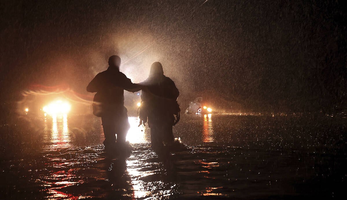 Sonoma County Fire's Eric Gromala guides a woman to safety after her vehicle stalled out in dee ...