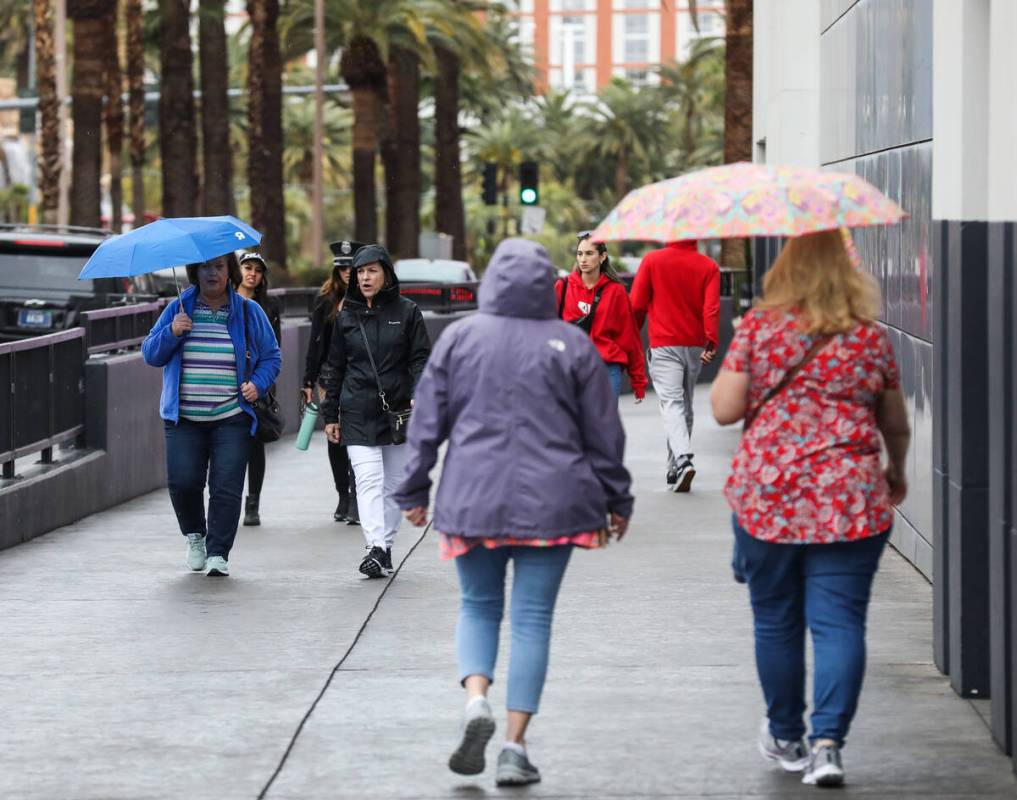 Pedestrians walk the Strip with umbrellas in Las Vegas, Tuesday, March 14, 2023. (Rachel Aston/ ...