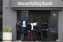 People look at signs posted outside of an entrance to Silicon Valley Bank in Santa Clara, Calif ...