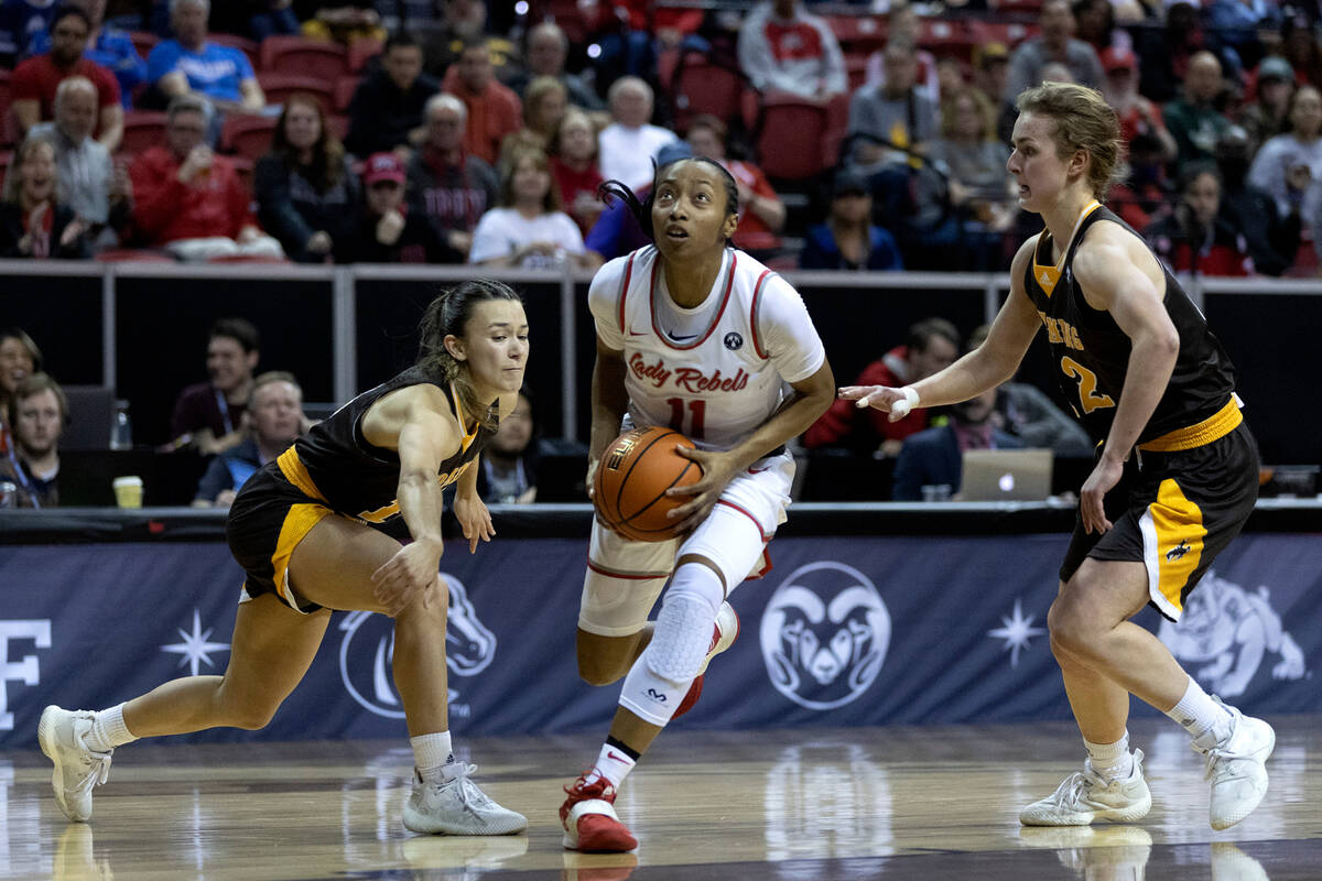 UNLV Lady Rebels guard Justice Ethridge (11) drives toward the hoop in between Wyoming Cowgirls ...