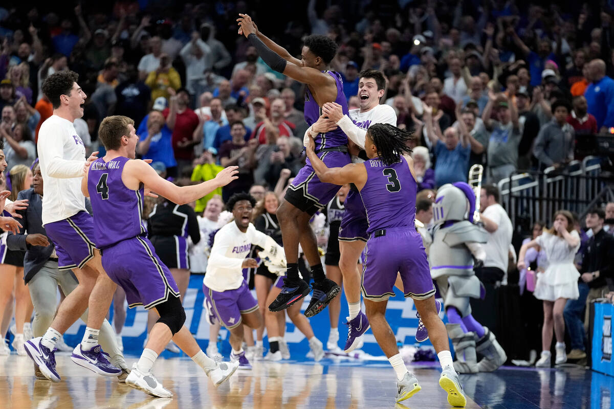 Furman guard JP Pegues, third from right, celebrates with the team after defeating Virginia in ...