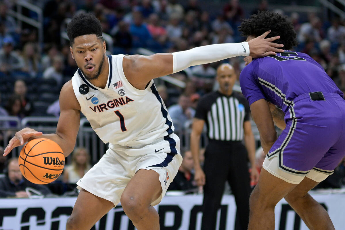 Virginia forward Jayden Gardner (1) drives past Furman forward Tyrese Hughey (15) during the fi ...