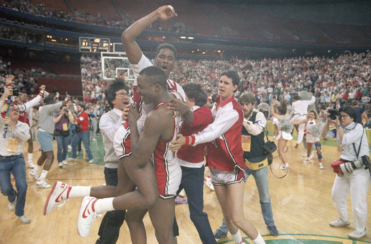 University of Nevada-Las Vegas forward Armon Gilliam (center) holds onto teammate Gary Graham, ...