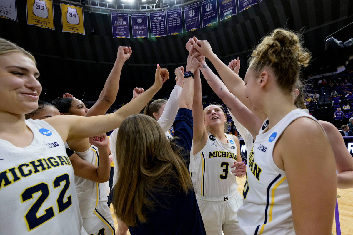 Michigan head coach Kim Barnes Arico, center, celebrates with her team including leading scorer ...