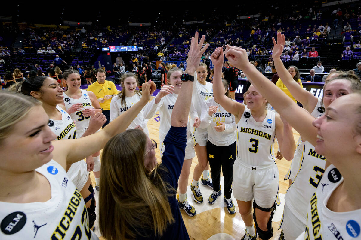 Michigan head coach Kim Barnes Arico, center, celebrates with her team, including leading score ...