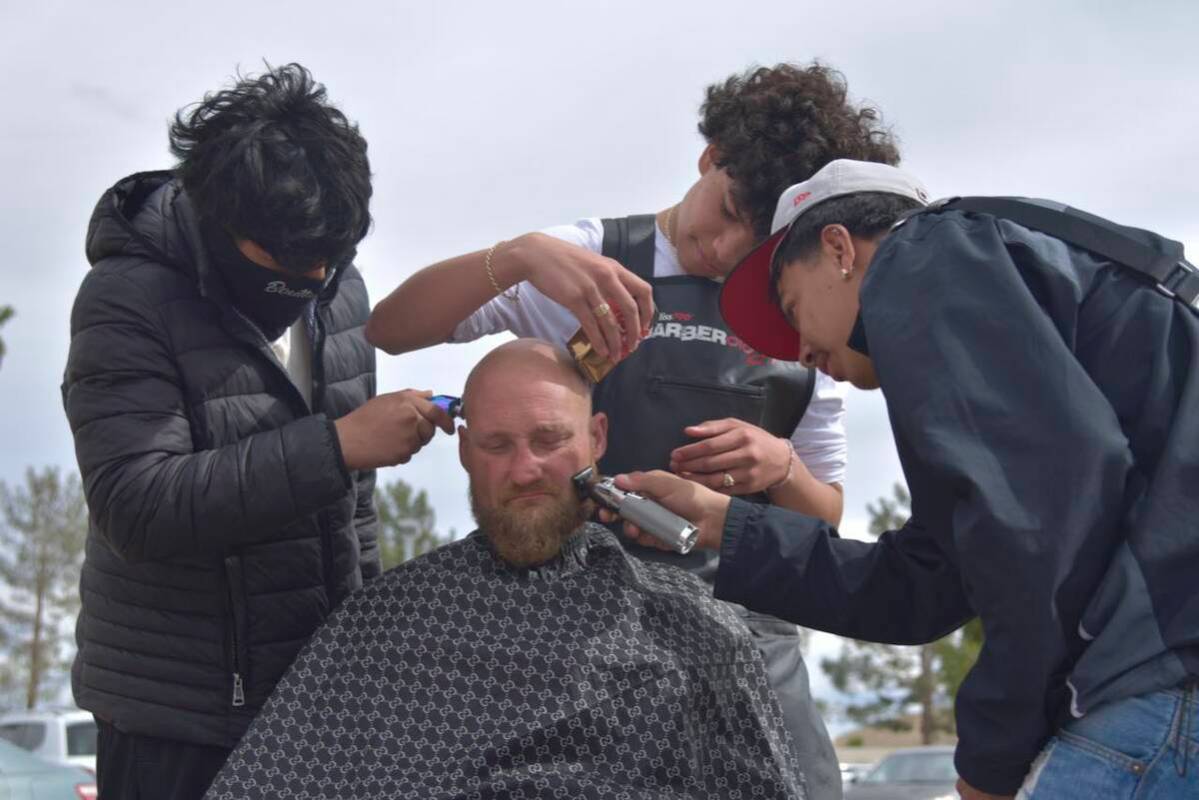 Richy Cruz, left, Gabriel Lopez, middle, and Joshua Polo, right, give a man a free haircut near ...