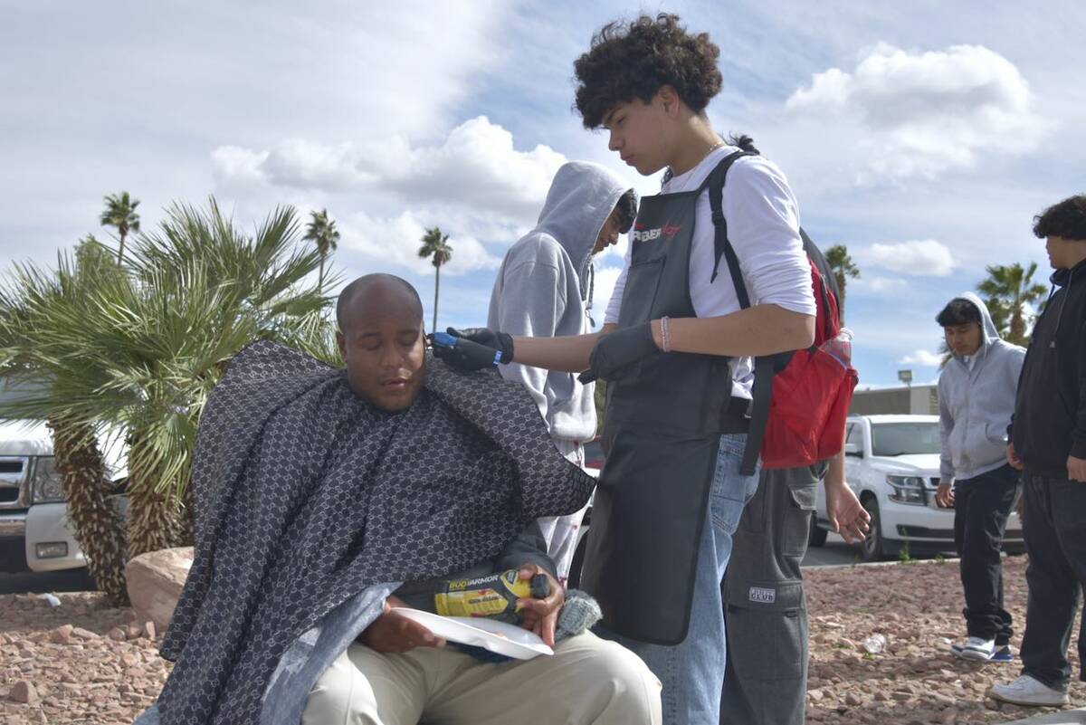 Gabriel Lopez, right, gives Ricky Porger Jr. a haircut as he eats a slice of pizza on the sidew ...