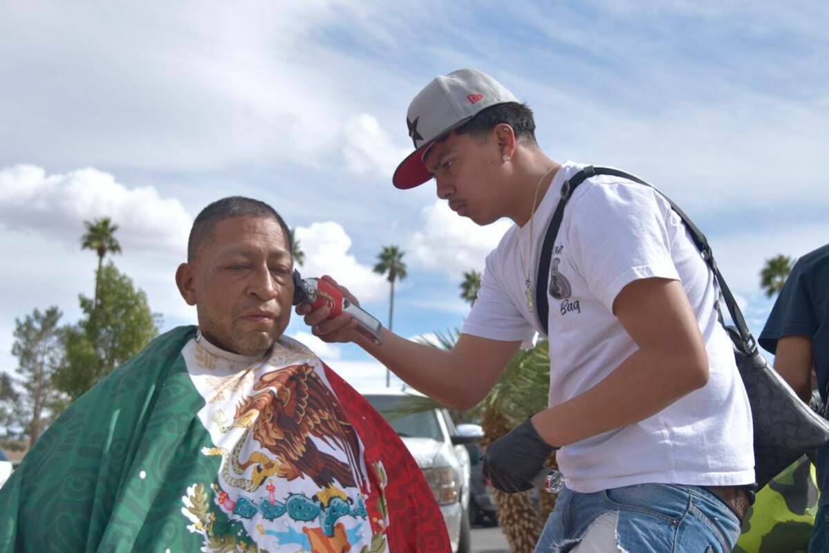 Jose Rodriguez, left, gets a haircut from Joshua Polo, right, on the sidewalk near Main Street ...